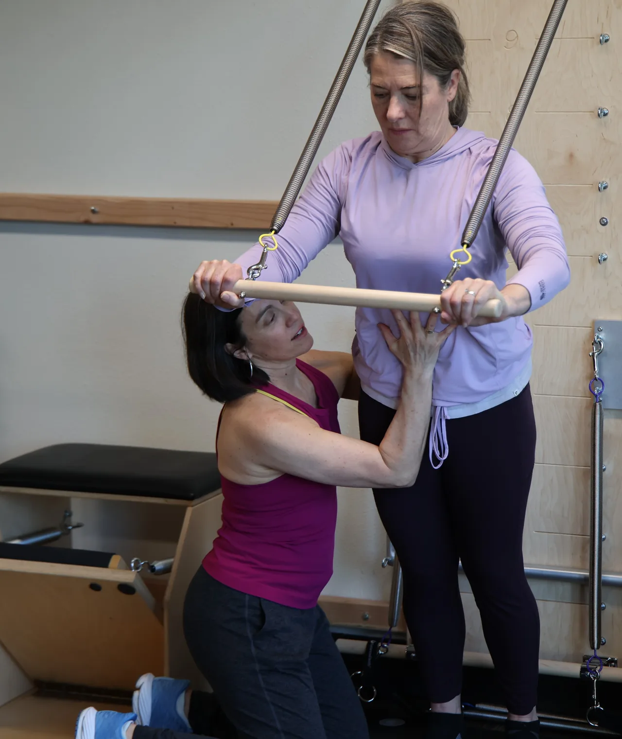 A Core Wisdom instructor guiding a client one-on-one on the Pilates tower in Boulder